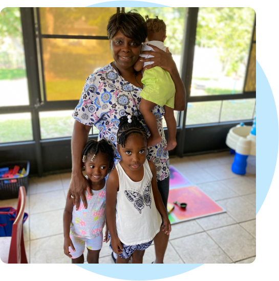SHARON SINGLETON stands in her early learning center with three of her students. It is brightly lit, and she is smiling.